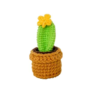 Handmade crochet cactus plant in orange pot with yellow flower and knitted soil texture