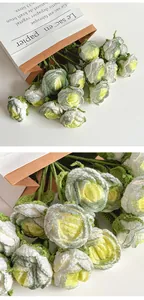 Close-up of handmade crochet roses with white petals and green leaves in kraft paper bag