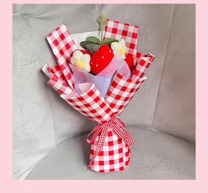 Détail d'un bouquet de fraises au crochet fait main avec emballage à carreaux rouges
