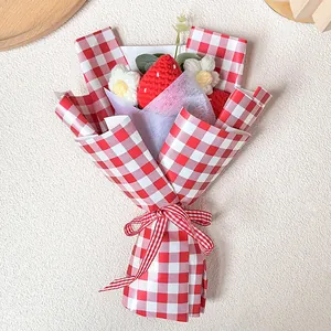 Bouquet de fraises et fleurs au crochet fait main dans un emballage cadeau à carreaux