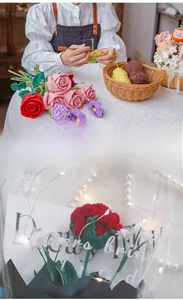 Detailed macro view of handmade knitted flower bouquet with crochet tools and accessories