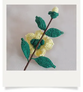 Gros plan détaillé du camélia au crochet fait main avec pétales jaunes et feuilles