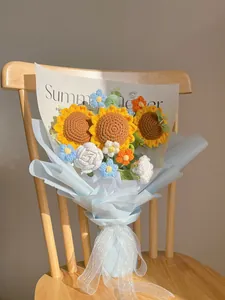 Detail of handcrafted knitted sunflower bouquet with blue gift wrapping on a chair