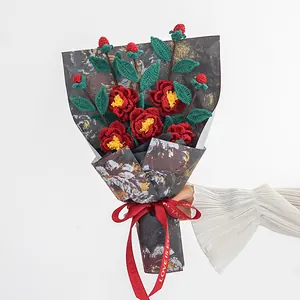 Bouquet de camélias au crochet fait main avec roses rouges dans un emballage cadeau chic