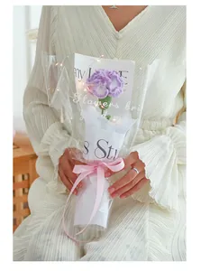 Detail of hand-knitted purple carnation with LED string lights in premium gift packaging