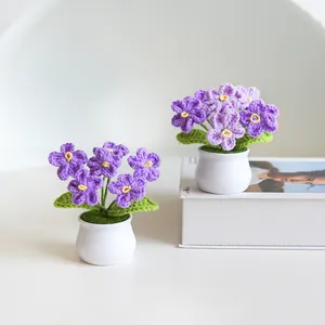 Two handmade knitted forget-me-not potted plants with purple flowers and white pots