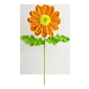 Detail of handcrafted crochet sunflower with vibrant orange petals and green stem