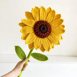 Close-up of a large handmade crochet sunflower with vibrant yellow petals and green leaves
