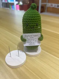 Detail van de handgebreide Emotional Support Pickle met kaart en houten standaard