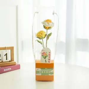 Détail d'un bouquet de roses tricotées à la main dans une boîte cadeau transparente