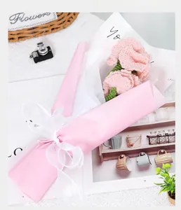 Hand-knitted pink tulip bouquet in premium packaging on a decorative book background