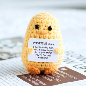 Macro shot of a handmade yellow crochet positive duck holding an inspirational card