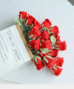 Gros plan d'un bouquet de roses rouges au crochet fait main sur fond blanc texturé
