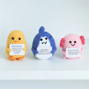 Close-up of handmade crochet shark, duck and axolotl plushies with positive quote cards