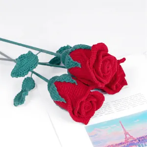 Gros plan de trois roses rouges faites à la main au crochet sur un magazine romantique