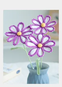 Detail of hand-knitted purple daisy crochet flowers in a striped blue ceramic vase