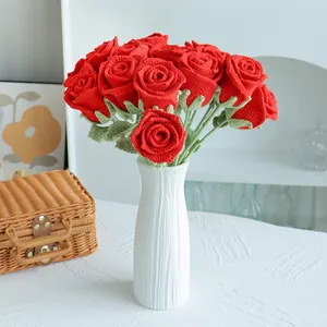 Bouquet de roses rouges au crochet fait main dans un vase en céramique blanche