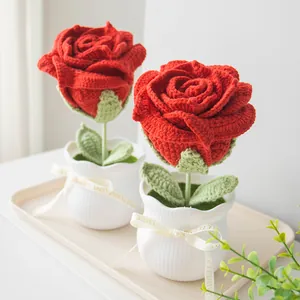 Detail of two handmade crochet red roses in white ceramic pots with elegant ribbon bows