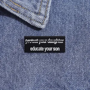 Detail der educate your son Emaille-Anstecknadel auf blauem Jeansjackenkragen
