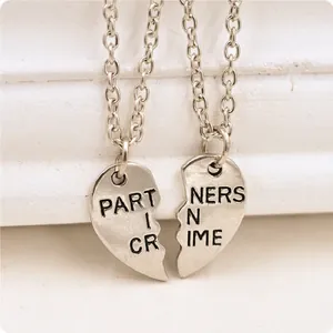 Silver broken heart pendant necklace set with Partners in Crime engraving on white wood