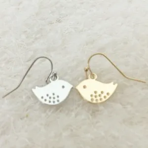 Detailed view of minimalist bird dangle earrings in gold and silver on white fabric