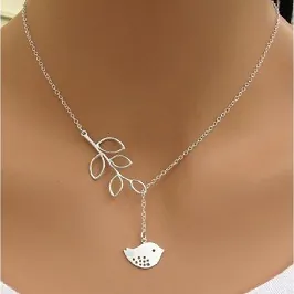 Detail of silver branch and bird pendant necklace worn to show delicate size and texture