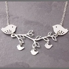 Detail of silver branch and birds pendant necklace on dark stone background