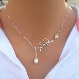 Detail view of silver branch necklace with round and teardrop pearls worn by a model
