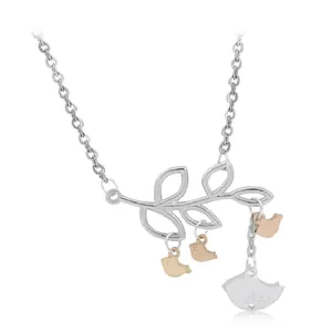 Detailed close-up of twig and bird pendant necklace with silver and gold tones