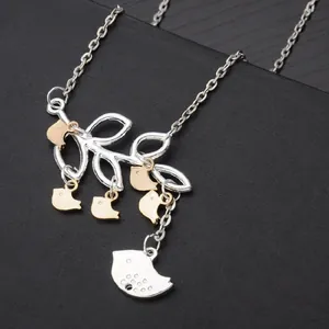 Macro view of silver tree branch necklace with five gold birds and large bird pendant