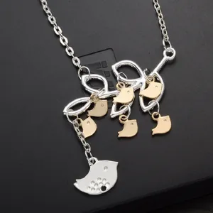 Detailed close-up of bird pendants necklace featuring mixed gold and silver tones