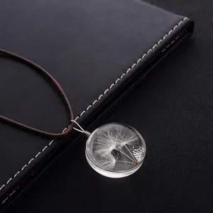 Détail du pendentif en verre avec graines de pissenlit et cordon tressé marron
