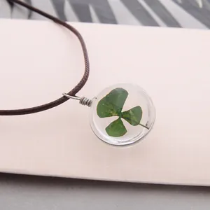 Détail du collier artisanal avec un véritable trèfle à quatre feuilles en résine ronde