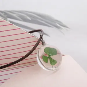 Vue macro d'un pendentif en résine avec trèfle à quatre feuilles et cordon tressé