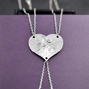 Detailed view of three-piece heart puzzle pendants with silver brushed metal finish
