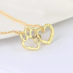 Macro shot of gold-plated dog paw and heart pendant necklace with hammered texture