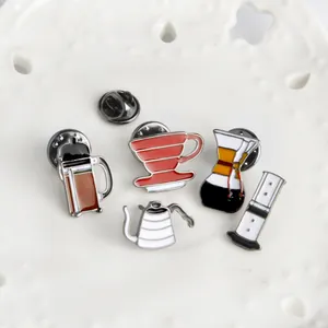 Detailed close-up of colorful coffee brewing equipment enamel pins on a white lace plate
