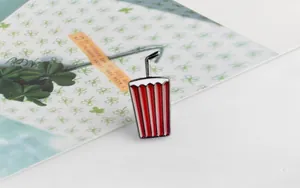 Detail showing cartoon enamel beverage pin with red stripes and black straw on a card