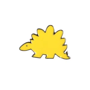 Détail macro du pin's dinosaure émaillé jaune avec des contours en métal noir poli