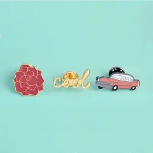 Detailweergave van de geëmailleerde speldjes met rode bloem, cool-tekst en retro auto