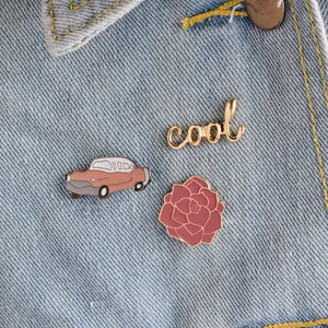 Driedelige emaille speldjes set met roze auto, bloem en cool tekst op denim jasje