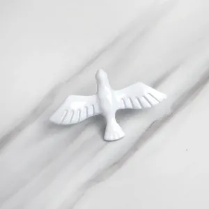 Minimalist white peace dove brooch pin on elegant white marble background