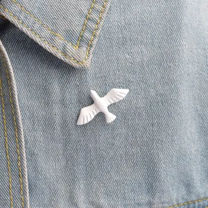 Cute white peace dove enamel brooch pin accessory on blue denim jacket lapel