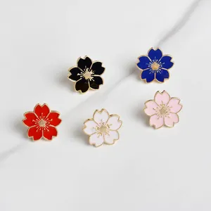 Set van vijf kleurrijke sakura emaille bloemspelden met gouden rand op marmeren blad