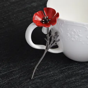 Detailed view of elegant red poppy flower brooch with metal stem on a ceramic cup