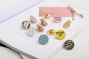 Nahaufnahme bunter runder Emaille-Pins mit Motivationssprüchen auf einem Buch