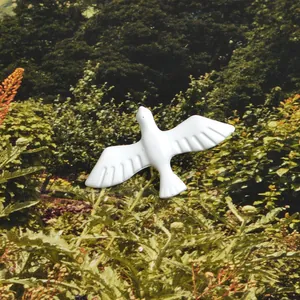 Detail of white dove brooch with enamel finish showing wing texture on floral background