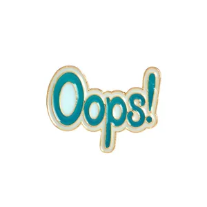 Detalle de broche esmaltado 'Oops!' con diseño azul y blanco y elegante borde dorado