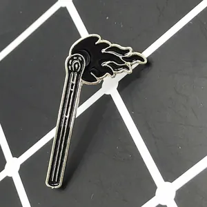 Close-up of minimalist black enamel flame matchstick brooch pin on grid background