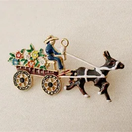 Detail einer Vintage-Emaille-Brosche mit Eselkarren, bunten Blumen und Strasssteinen